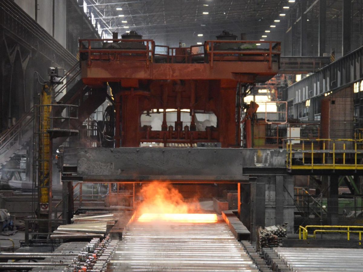 Stahlblechherstellung bei ArcelorMittal: Glühend heißer Stahl wird auf einem Rollband in eine Presse transportiert.
