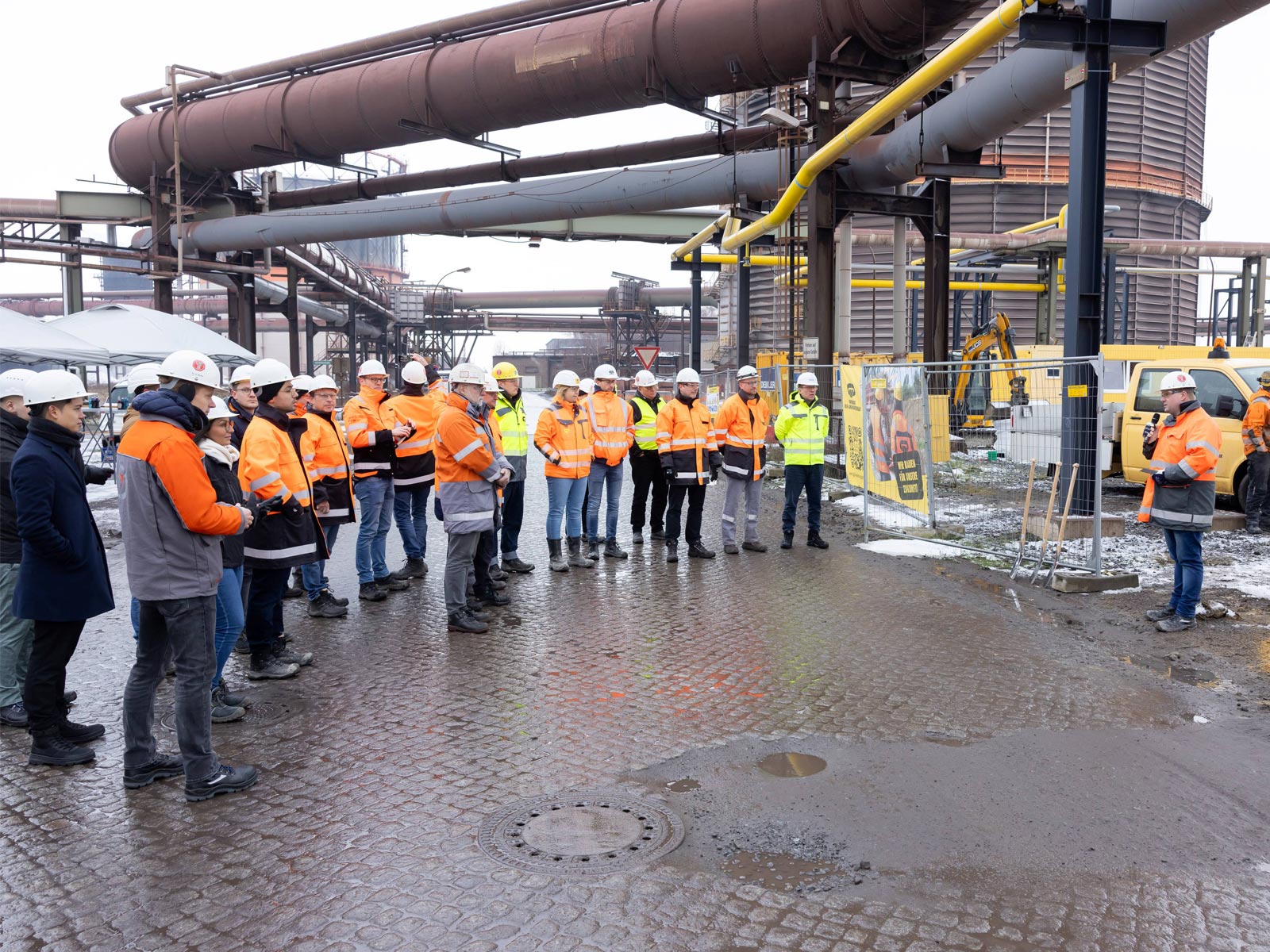 Zum Spatenstich des Hauptschalthauses der Direktreduktionsanlage in Salzgitter stehen viele Mitarbeiter aufgereiht vor einem Sprecher. Es ist der Erste Schritt des Programms SALCOS®.