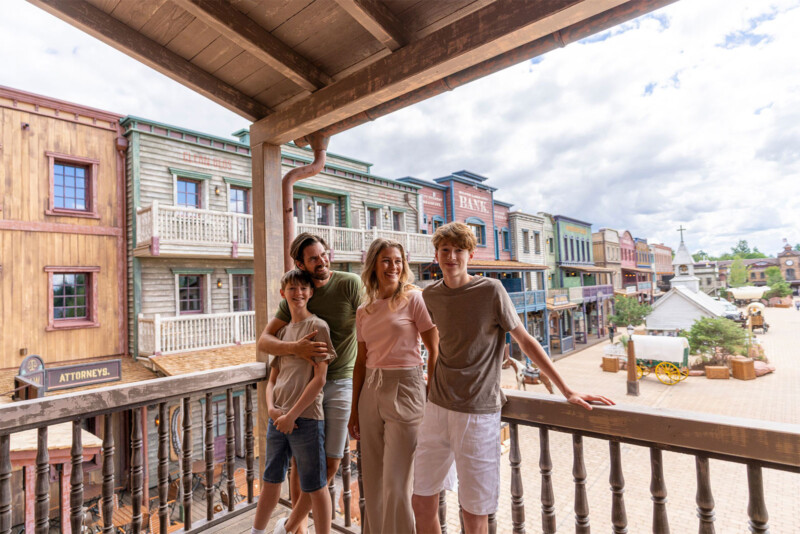 Familie genießt den Blick vom Balkon der Riverside Western Lodge auf die Häuserfront von Silver Lake City