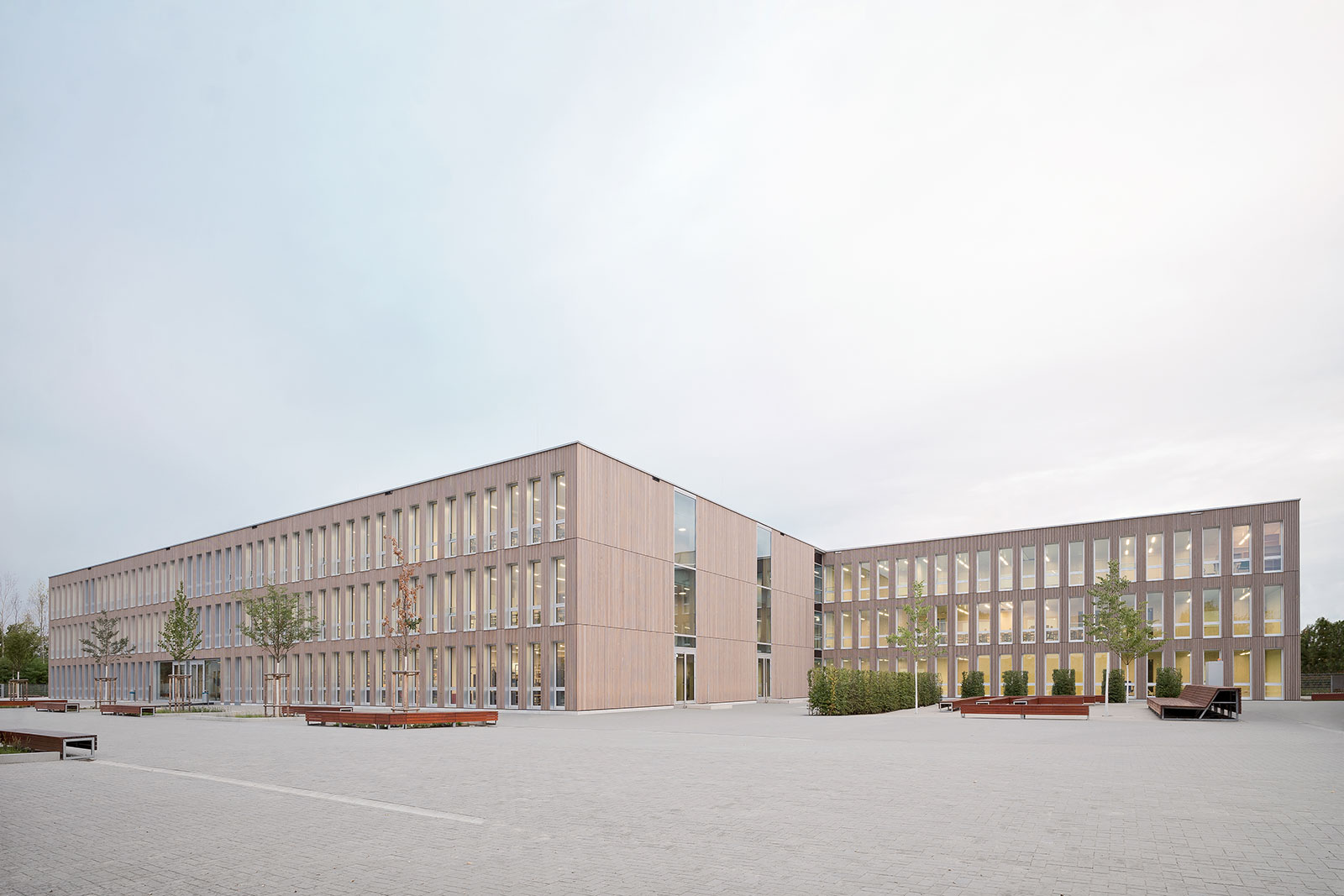Foto des Gymansium nord Frankfurt: Viele lange, schmale, hohe Fenster und die Holzbau Fassade prägen die Erscheinung.