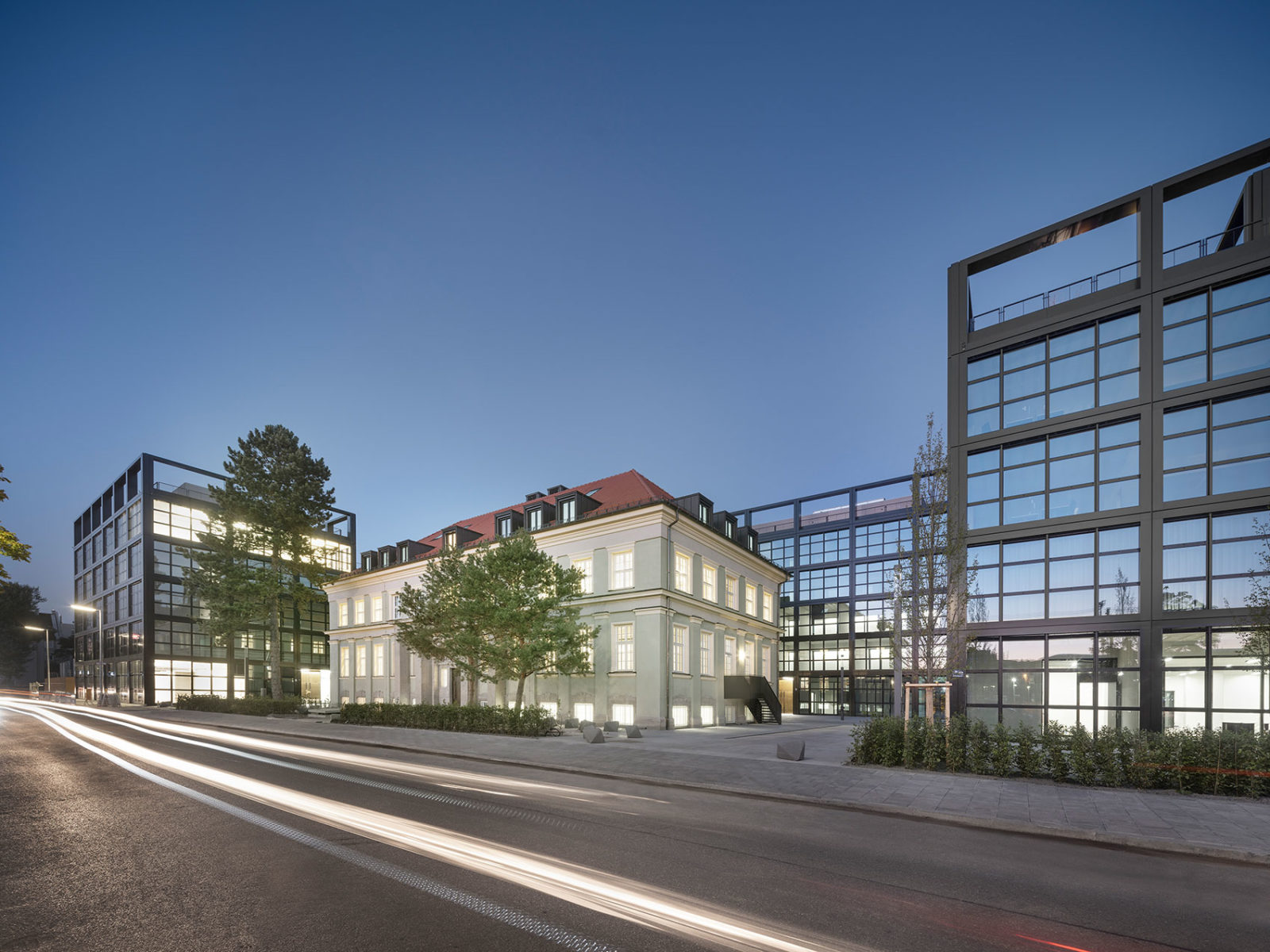 Die Gebäude i2 & i3 des iCampus in München umrahmen mit ihrer schlichten Glasfassade die 100-jährige Rhenania Villa.