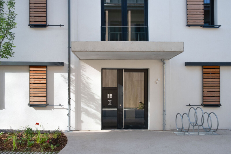Hauseingang mit Betonvordach, Holzfensterläden und Fahrradstellplatz