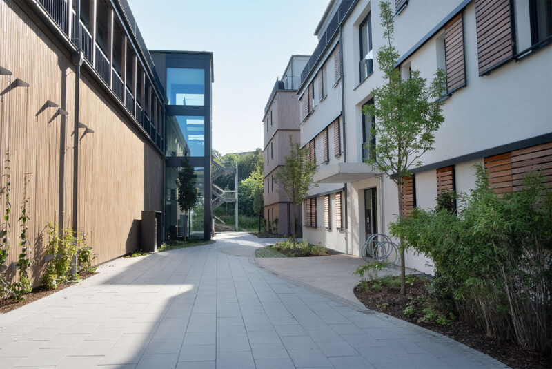 Verbindungsweg zwischen Wohnhäusern mit Glastreppenhaus und Holzfassade