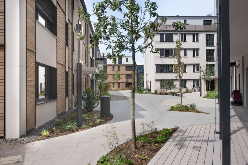 Zentraler Platz der Königsteiner Höfe mit Sitzbänken, Bäumen und umliegenden Wohnhäusern