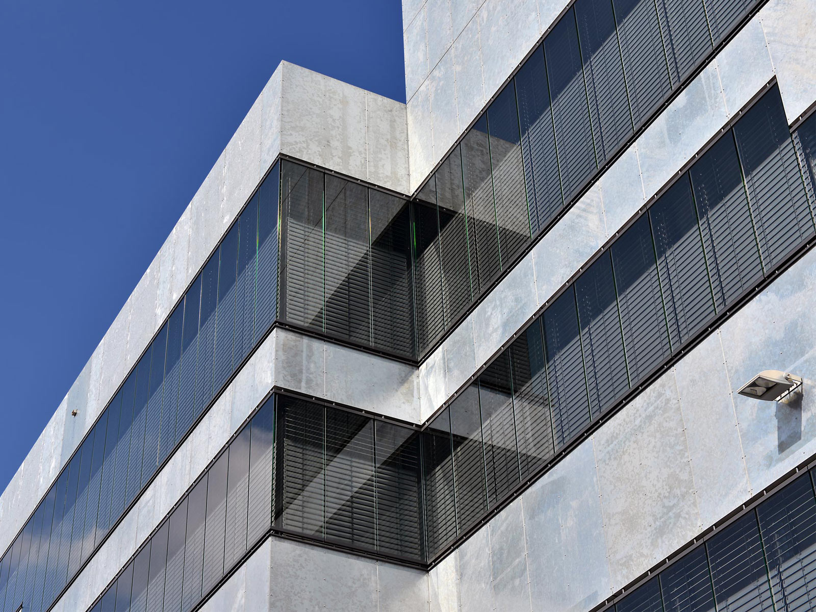 Gebäude von unten fotografiert: Graue Metallfassade und geschlossenen Jalousien