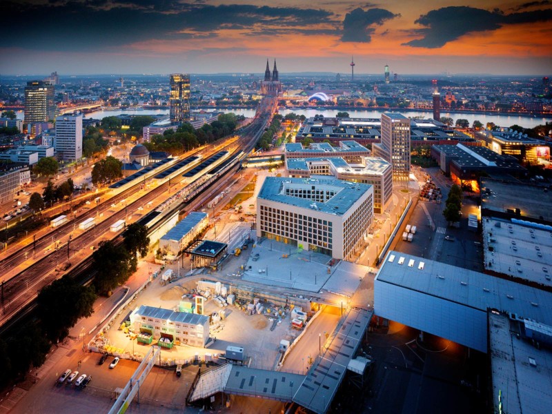 Luftaufnahme der MesseCity Köln bei Sonnenuntergang. Ein Gebäude im Vordergrund steht noch nicht