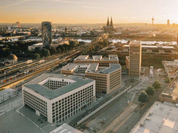 Bild der fertigen Gebäude der MesseCity Köln bei Sonnenuntergeang. Im Hintergrund ist die Innenstadt und der Dom zu sehen.