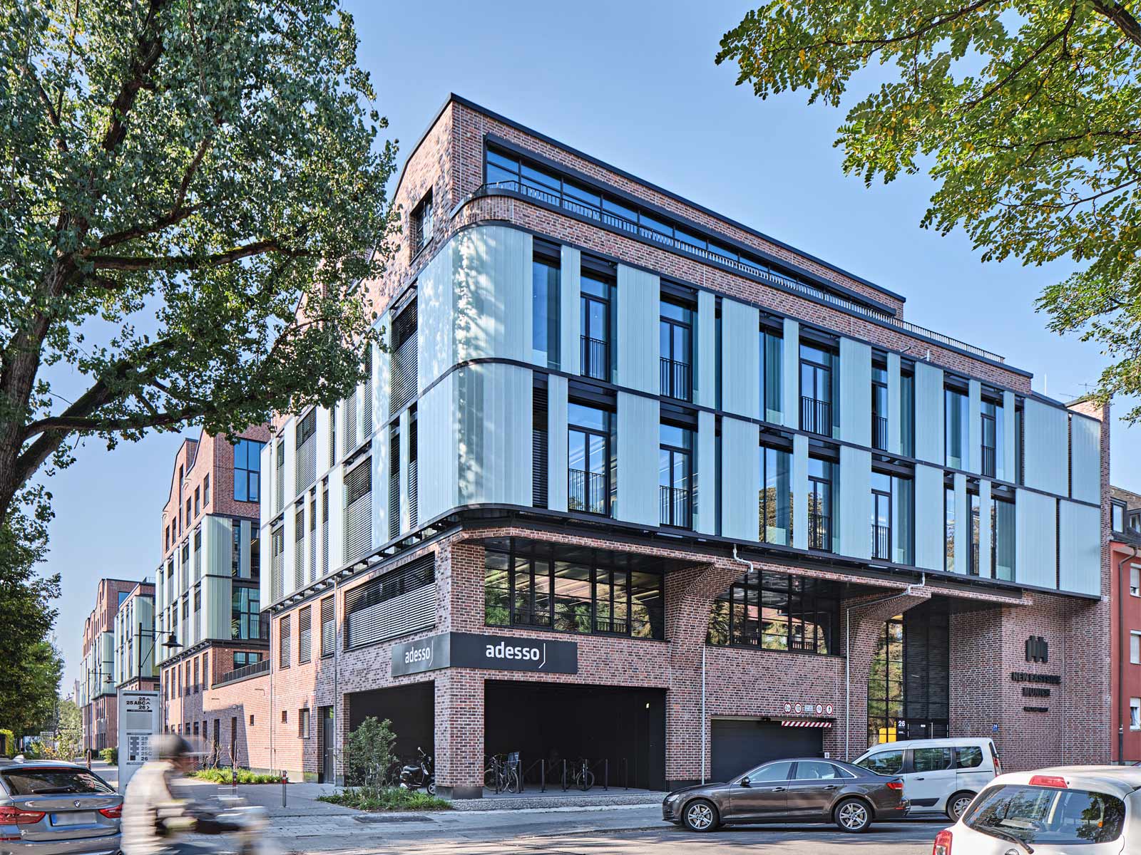 Ein Bild des Bürogebäudes New Eastside in München. Die rote Klinkerfassade wird durch einen Querstreifen Glasfassade unterbrochen.