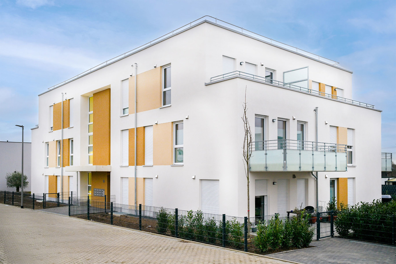 Neubau im Otterweg 16 in Pulheim: Das moderne Mehrfamilienhaus hat eine weiße Fassade mit gelben Akzenten