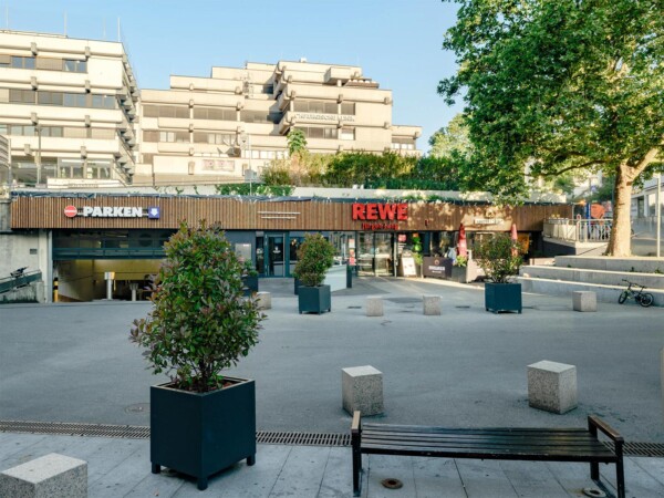 Rewe am Alten Postplatz in Waiblingen: Eingangsbereich mit Holzfassade, Dachbegrünung und Vorplatz mit Sitzbänken