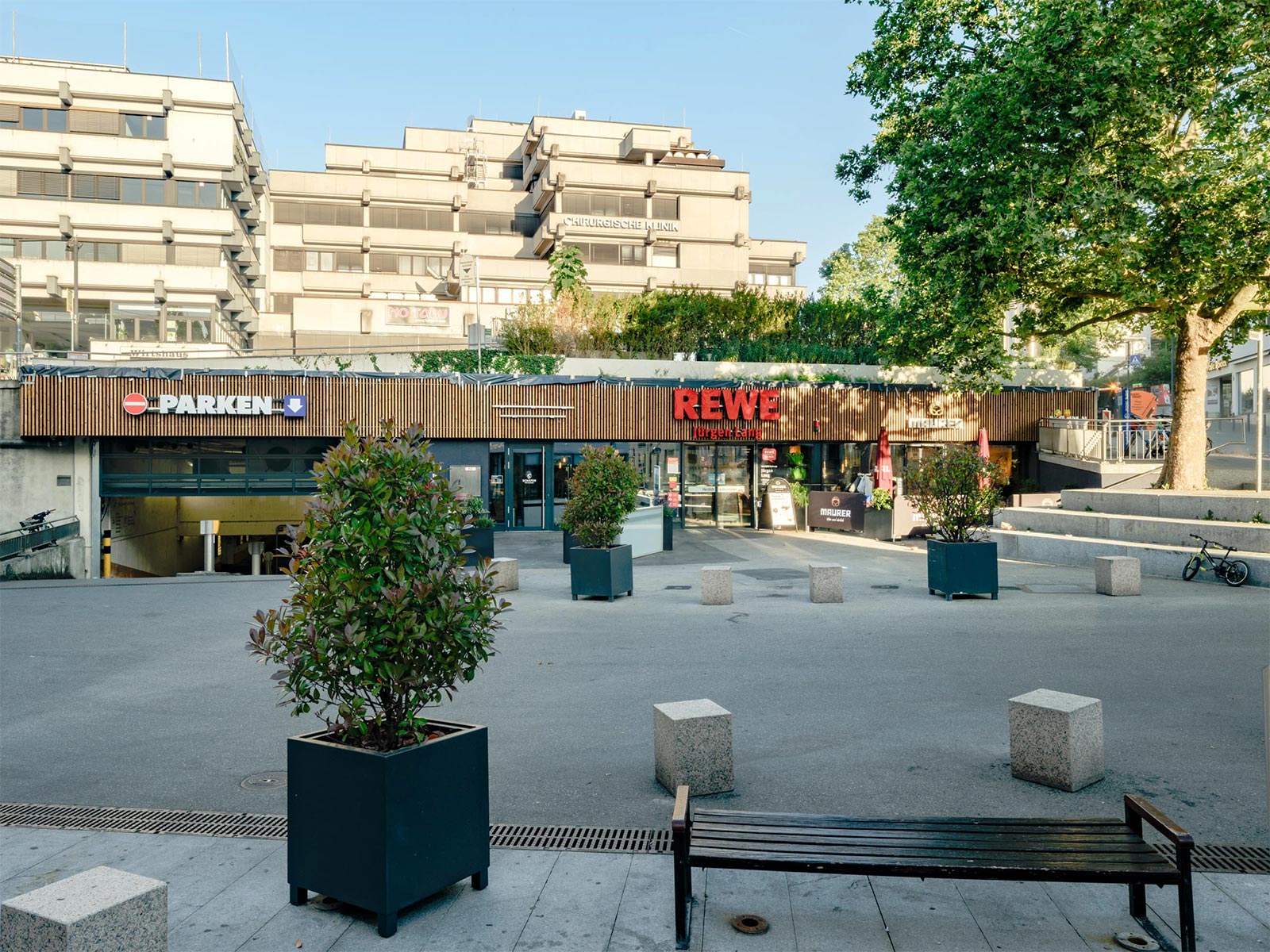 Rewe am Alten Postplatz in Waiblingen: Eingangsbereich mit Holzfassade, Dachbegrünung und Vorplatz mit Sitzbänken
