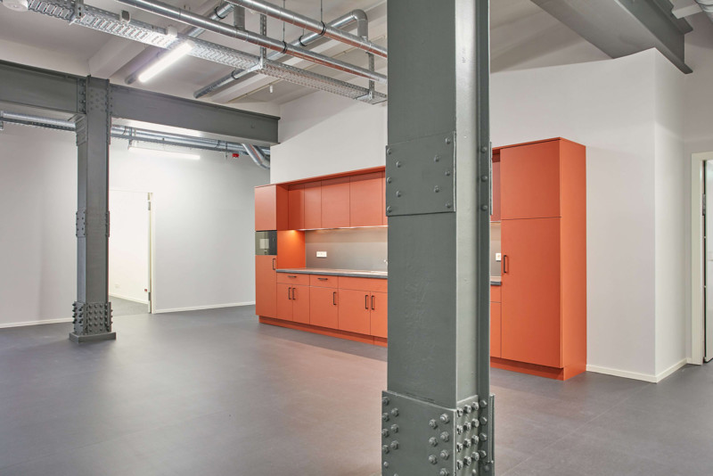 Eine orangene lange Küchenzeile in einem offenen Raum