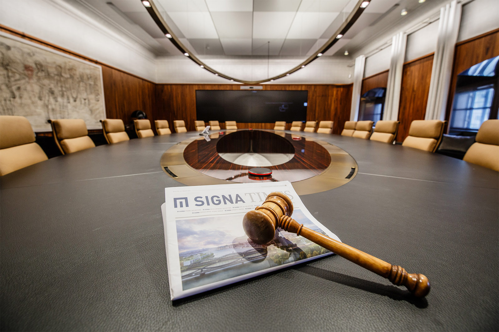 Ein Auktionshammer liegt symbolisch auf einem riesigen Konferenztisch: Die Versteigerung von Bürogegenständen der SIGNA Holding hat begonnen.