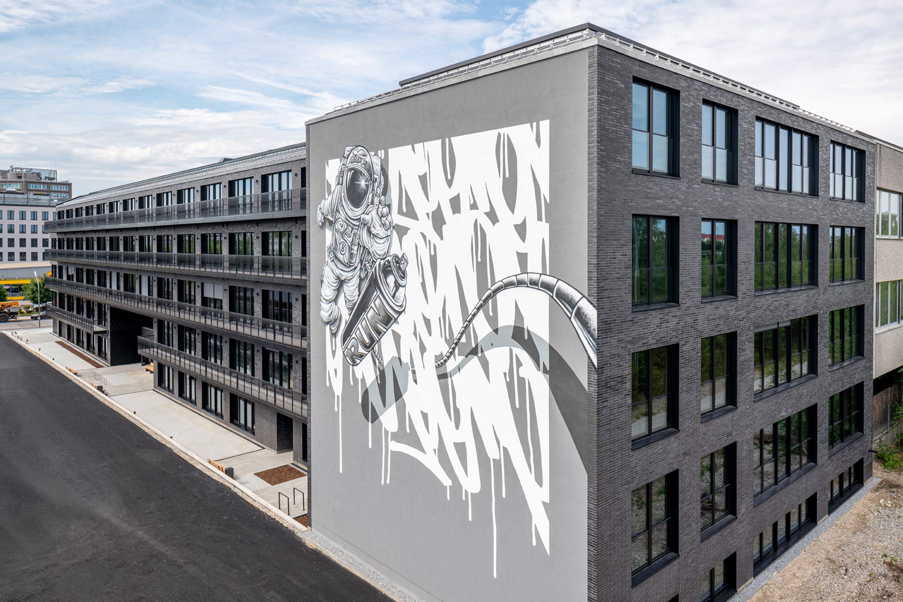 Auf einer Außenmauer des Bürogebäudes The Run in München ist ein großes Graffiti zu sehen: Ein Astronaut greift nach einer Spray-Dose.