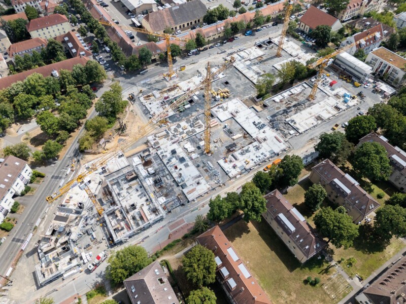 Luftaufnahme einer Großbaustelle mit mehreren Baukränen und Bodenplatten für ein neues Wohnquartier